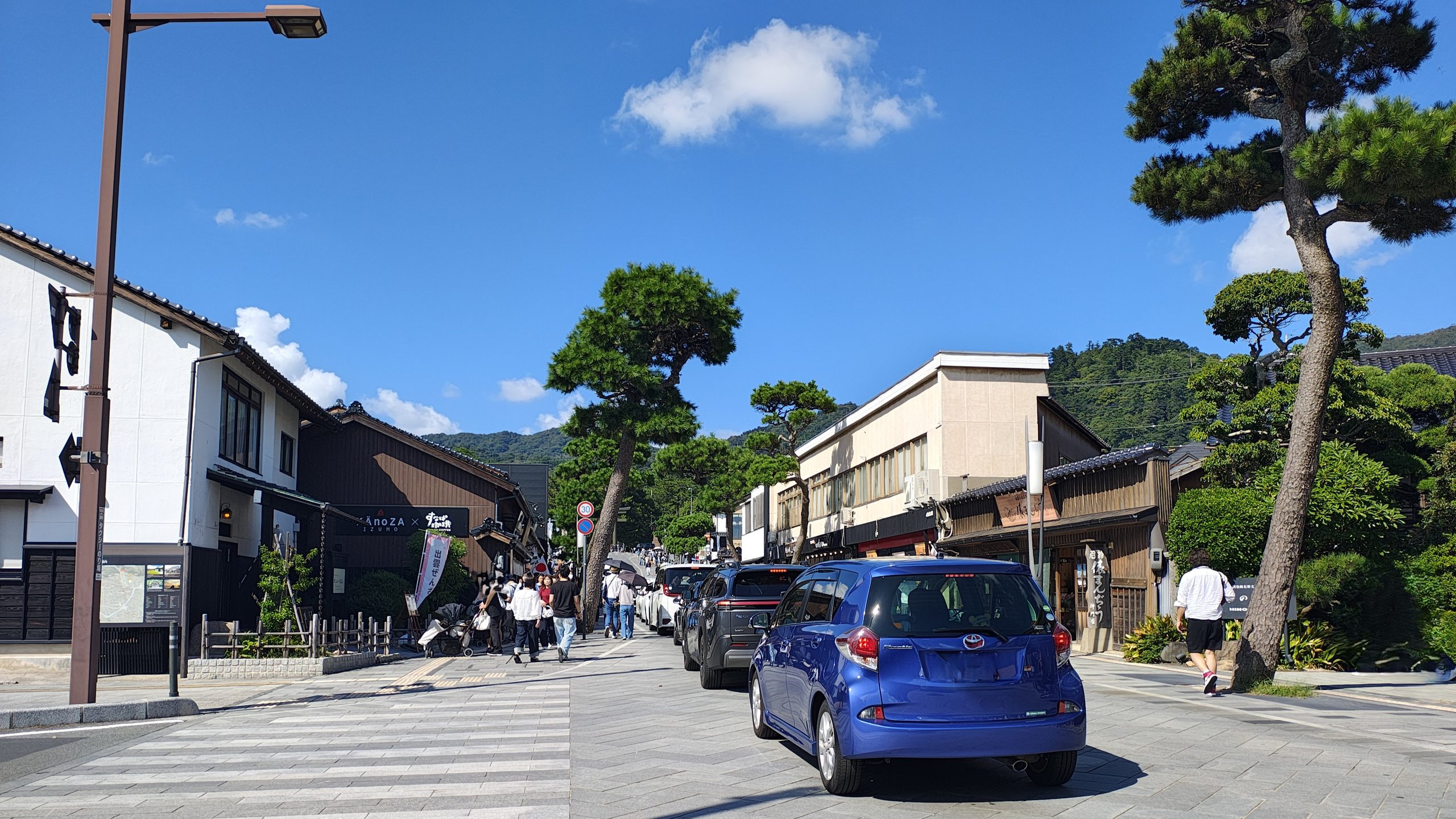 出雲大社周辺の神門通りを走る車と多くの歩行者
